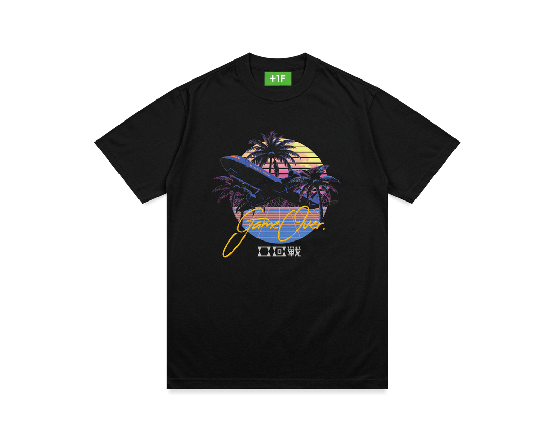 黒いTシャツの表面。中央に大きな飛行機のグラフィティ、その下にタイポグラフィされた「0回戦」の文字、上から「GAME OVER」の金色の刺繍重ねられたデザイン。襟タグは明るい緑色で白い「+1F」のロゴ入り。